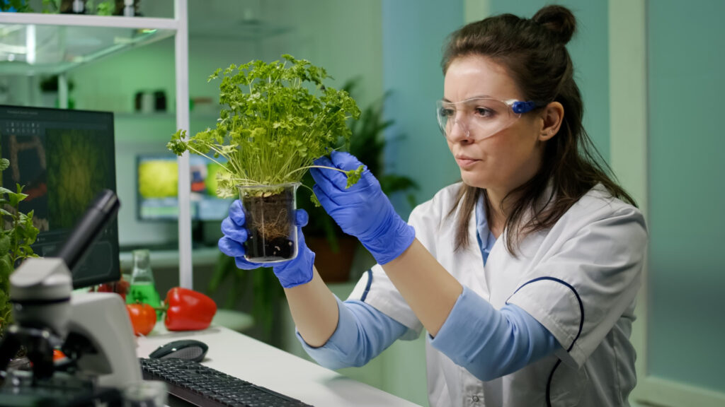 Estudiante de biotecnología en laboratorio utilizando microscopio para investigación científica en salud y medio ambiente.