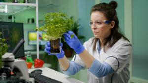 Estudiante de biotecnología en laboratorio utilizando microscopio para investigación científica en salud y medio ambiente.